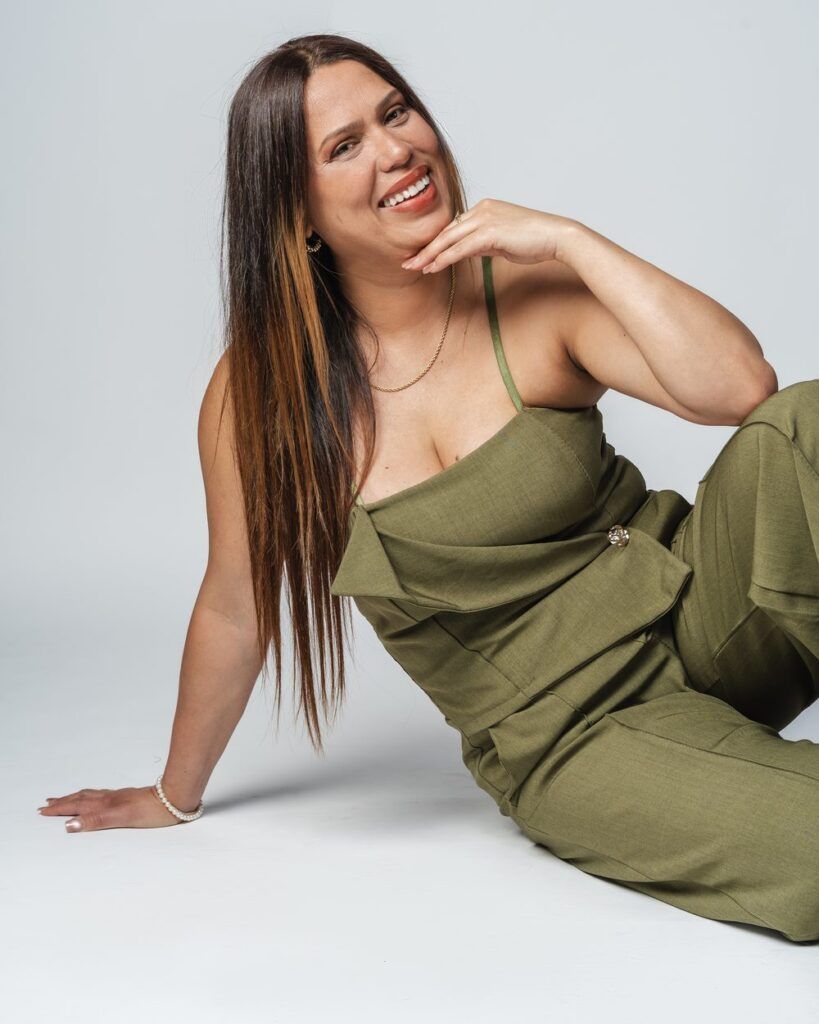 Paula Reynel sonriendo, sentada con un mono verde
